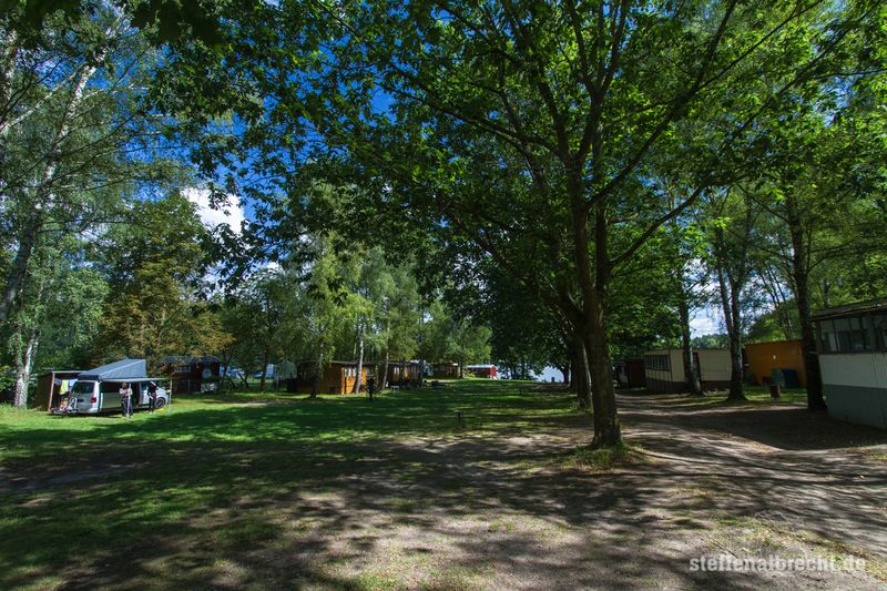 Foto Campingplatz: eine Wiese mit Bäumen und mehreren Holzhäuschen